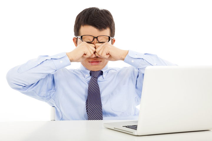 man at computer rubbing tired eyes